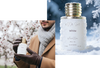 Perfume bottle with gold cap held by a person in winter clothing, against a snowy background.